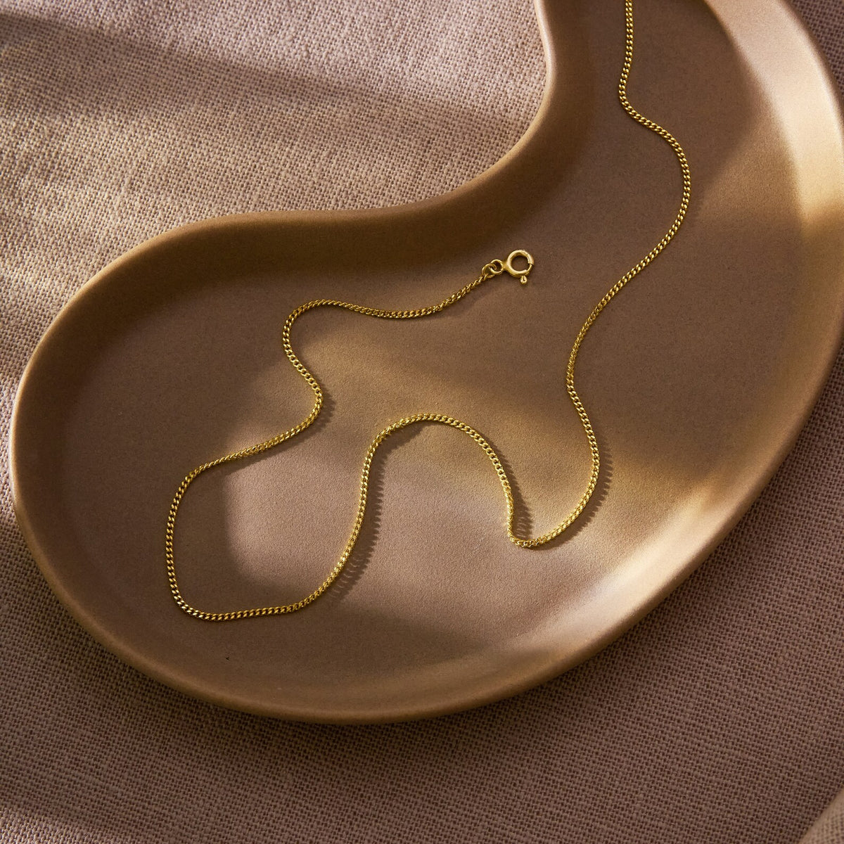 Bold Curb Chain Necklace, 14K gold vermeil, resting on a gold dish (1)