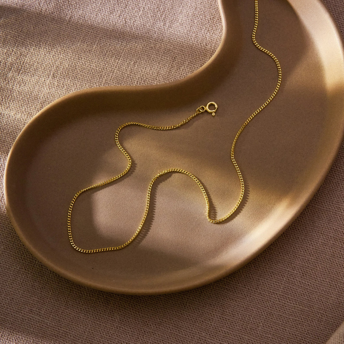 Thin Curb Chain Necklace, 14K gold vermeil, resting on a gold dish
