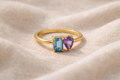 Two stone birthstone ring with prong set emerald-cut and pear-cut stones