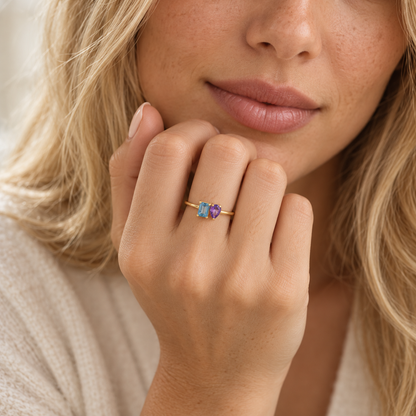 Hand wearing custom two stone birthstone ring with emerald-cut and pear-cut stones