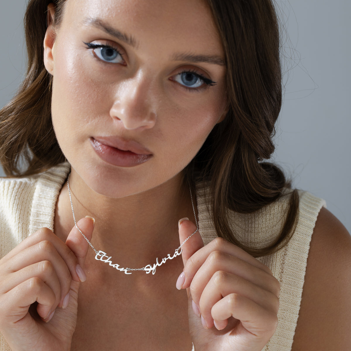 Personalized two name necklace in silver finish with two cursive names on a dainty chain, worn on the neck